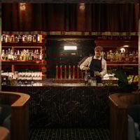 The barman measures out the ingredients for a cocktail behind Fugazzi's signature burgandy marble bar.